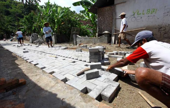 Sejumlah warga menyelesaikan proses pemasangan paving block di jalan Desa Margodadi, Seyegan, Sleman, DI Yogyakarta, Kamis (17/3).